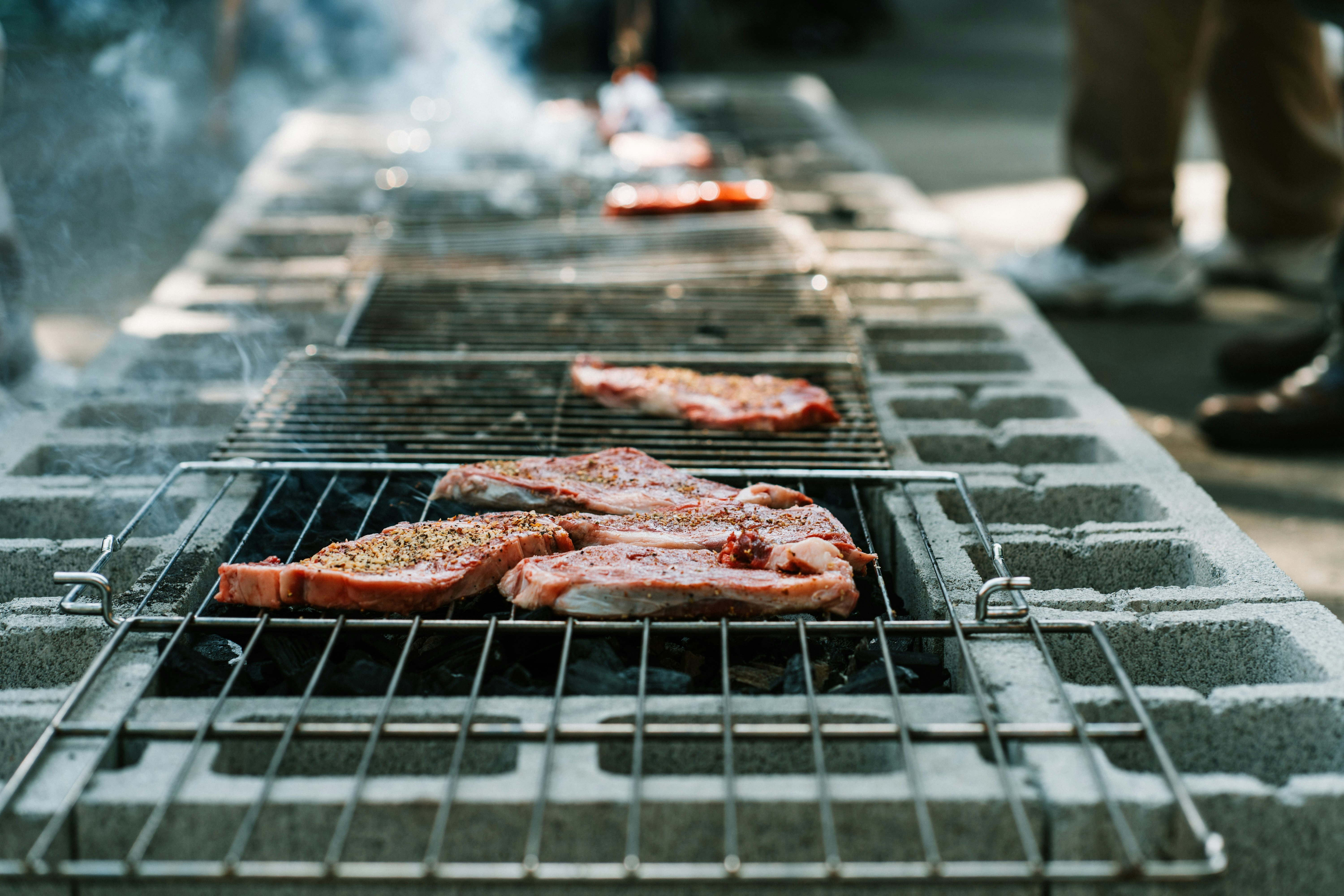 person grilling meat outdoor during daytime